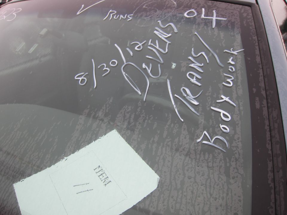 Windshield with white chalk writing including dates and 'Body work'