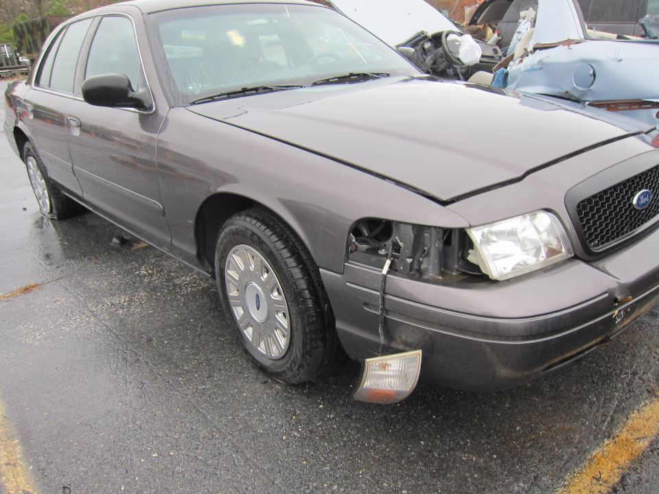 Gray 2001 Ford Crown Victoria front view with missing headlight and detached turn signal