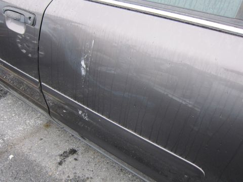2001 Ford Crown Victoria - Side view of a gray car door with visible damage and water streaks.