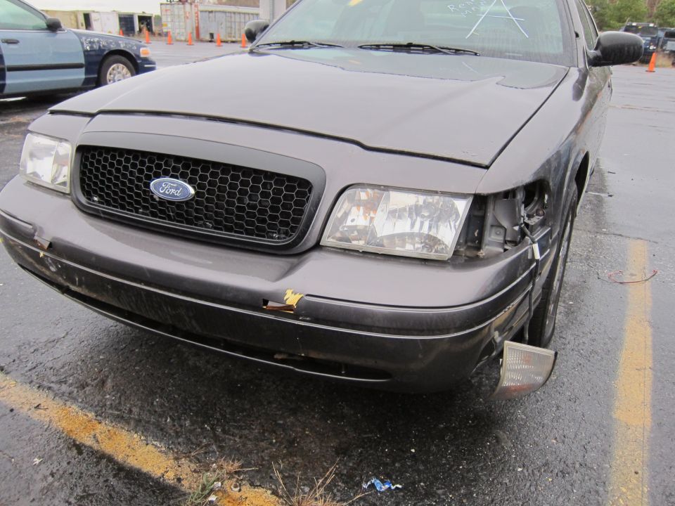Front of a dark gray 2001 Ford Crown Victoria with a damaged bumper and missing headlight