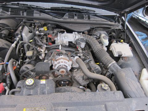 2001 Ford Crown Victoria - The engine bay of a vehicle, showing the alternator, intake manifold, and various hoses and wiring.