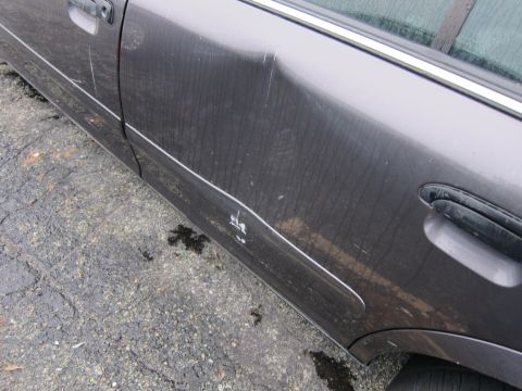 2001 Ford Crown Victoria - Side view of a damaged car door with visible dents and scratches.