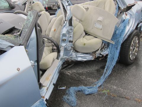 2001 Ford Crown Victoria - The interior of a heavily damaged sedan is visible, with blue netting spilling out from the passenger side.