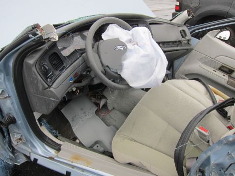 2001 Ford Crown Victoria - The interior of a 2001 Ford Crown Victoria shows a deployed airbag and significant damage to the dashboard and driver's side.