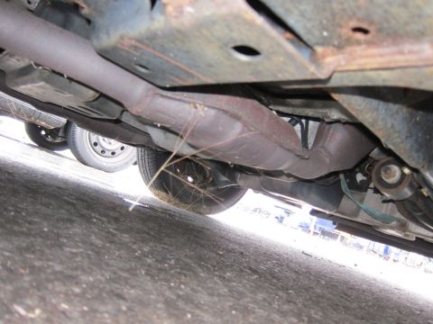 2001 Ford Crown Victoria - The undercarriage of a vehicle, including the exhaust pipe and catalytic converter, is shown from a low angle.