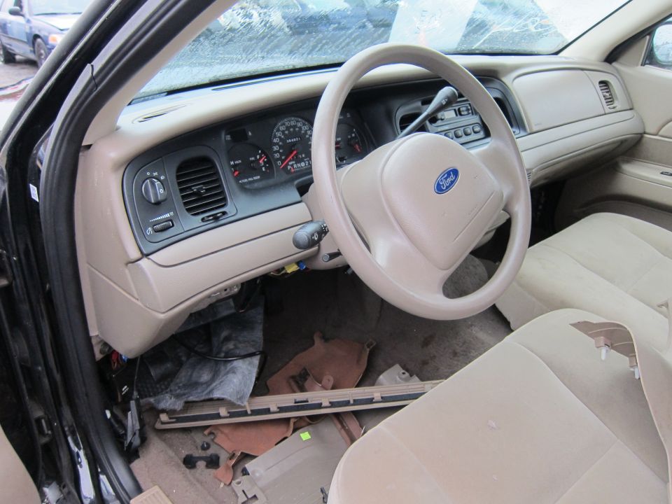 Interior of a 2001 Ford Crown Victoria showing dashboard, steering wheel with Ford logo, and tan seats