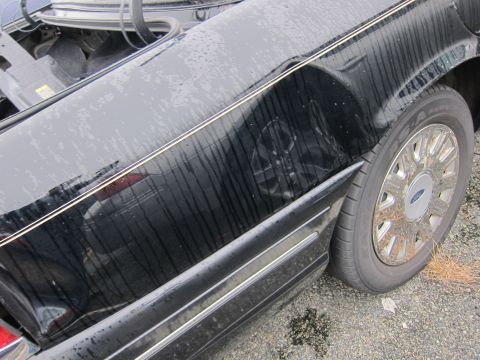 2001 Ford Crown Victoria - Side view of a black 2001 Ford Crown Victoria, showing the fender and wheel.
