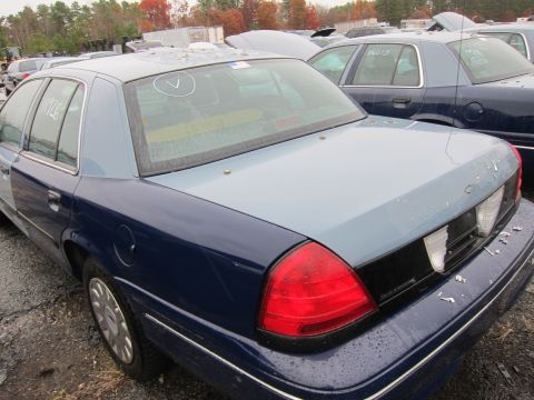 2001 Ford Crown Victoria - A two-tone sedan, possibly a Ford Crown Victoria, is seen in a junkyard with markings on its windows.