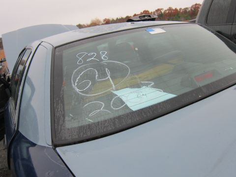 2001 Ford Crown Victoria - Chalk markings and a paper tag are visible on the rear window of a car in an outdoor lot.