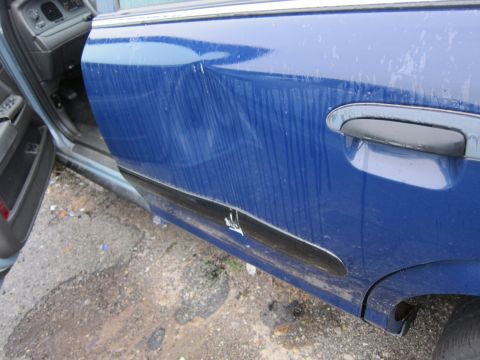 2001 Ford Crown Victoria - Close-up of a blue sedan's side door, showing damage and interior details.