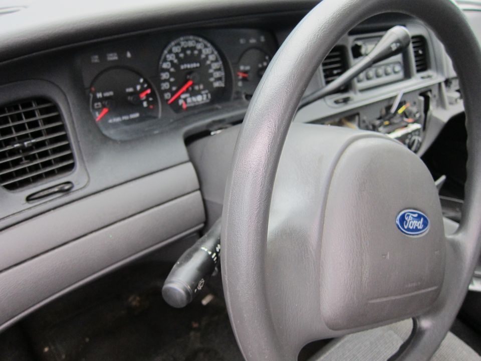 Interior of a 2001 Ford Crown Victoria showing the steering wheel with Ford logo and dashboard gauges