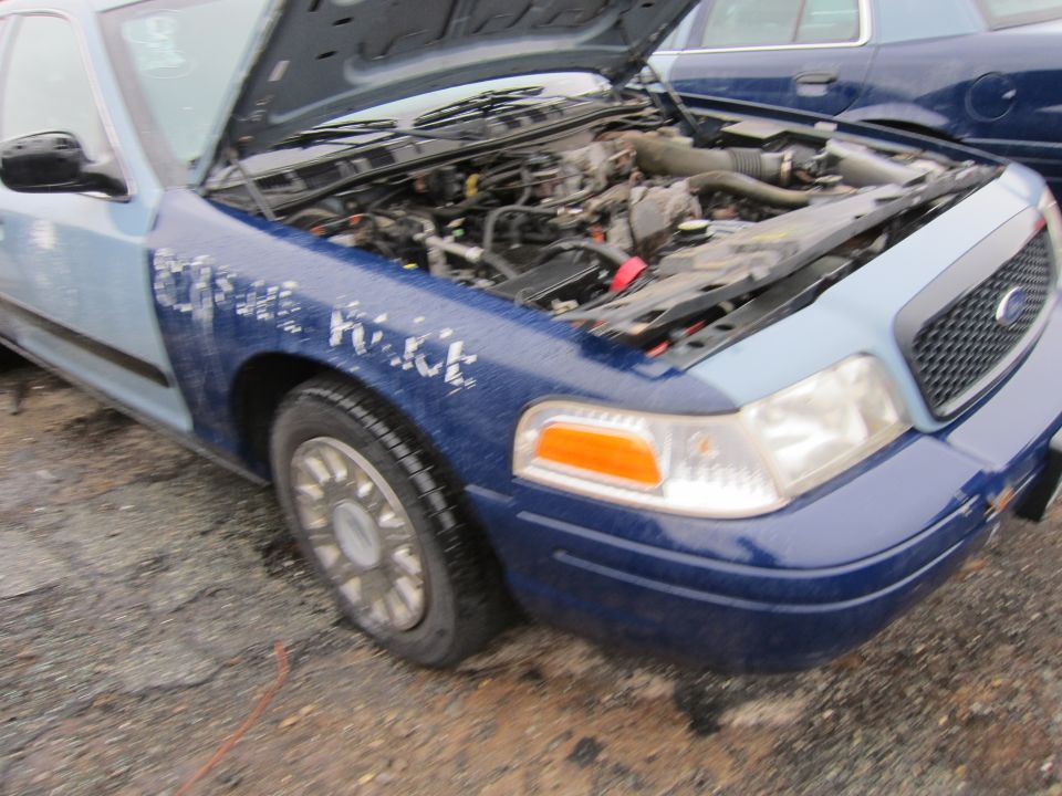 Blue and light blue Ford Crown Victoria Police Interceptor with hood open, showing engine. Text 'POLICE' visible on fender
