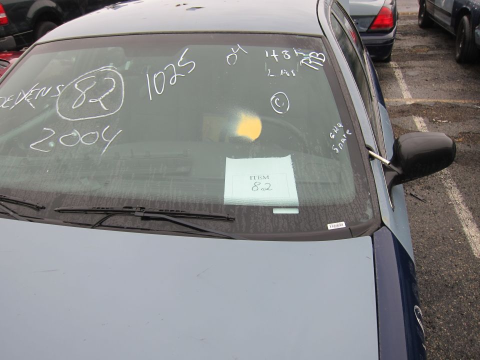 car windshield with chalk markings '2004' and '1025', and a paper tag that says 'ITEM 82'