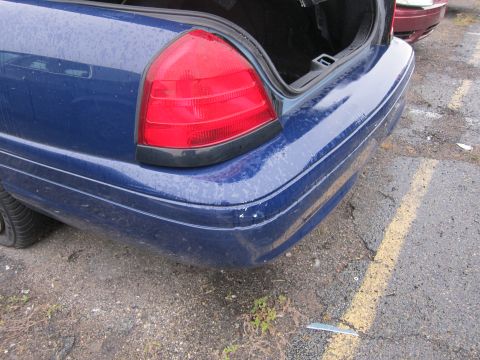 2001 Ford Crown Victoria - Rear view of a blue 2001 Ford Crown Victoria with its trunk open, parked next to another vehicle.
