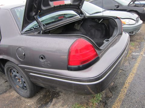 2001 Ford Crown Victoria - The rear of a gray sedan is shown with its trunk open. Another vehicle is visible in the background.