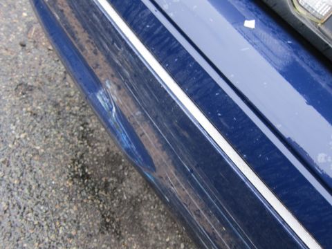 2001 Ford Crown Victoria - Close-up of a damaged blue car bumper with visible scratches and a dent.