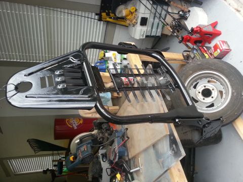 1994 Ford Bronco - A vehicle frame part and tire are shown in a garage setting with tools and fishing rods in the background.