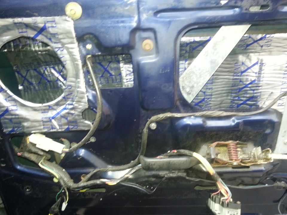 Inside of a car door with wiring and sound dampening material visible