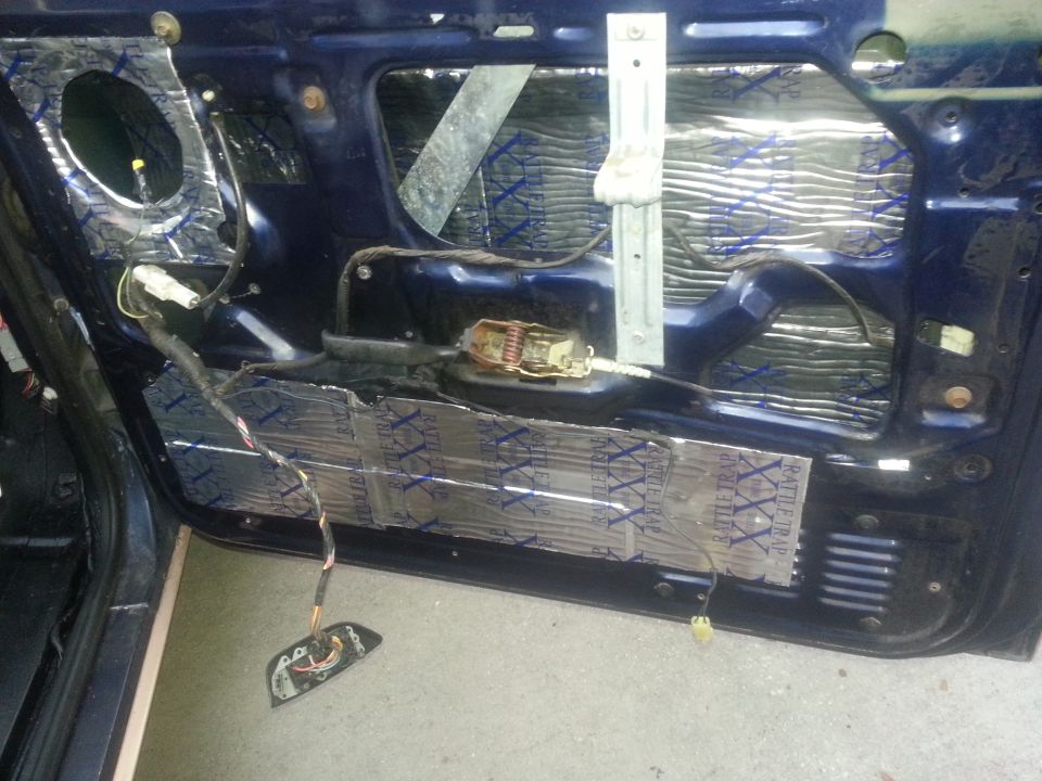 Car door interior with sound dampening material and exposed wiring