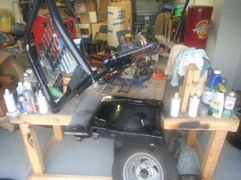 1994 Ford Bronco - Vehicle parts are disassembled and organized on sawhorses in a cluttered garage setting.