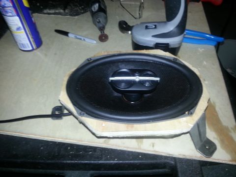 1994 Ford Bronco - Car speaker and tools are on a workbench, suggesting a car audio installation or repair.