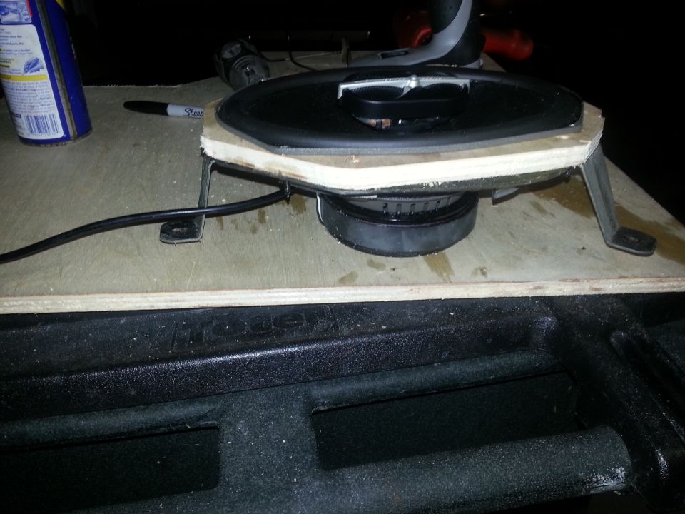 car speaker mounted on wood with brackets, wires connected, next to a can and marker