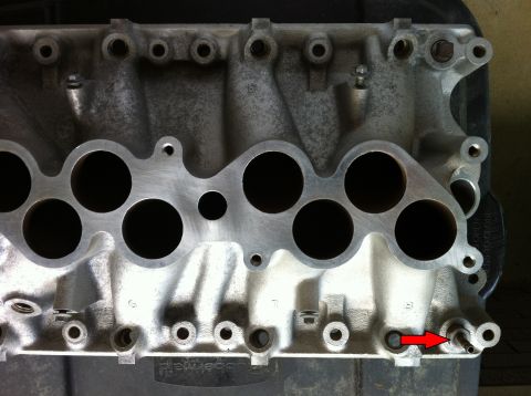 1992 Ford Bronco - Close-up of an aluminum intake manifold, showing its ports and a detail highlighted by a red arrow.