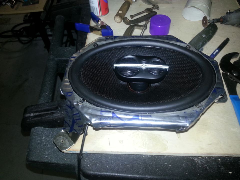 Car speaker with silver trim on a workbench, surrounded by tools