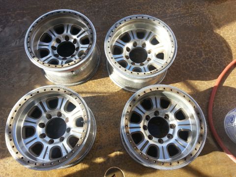 1995 Ford Bronco - Four aluminum alloy wheels with beadlock rings are laid out on a textured surface.