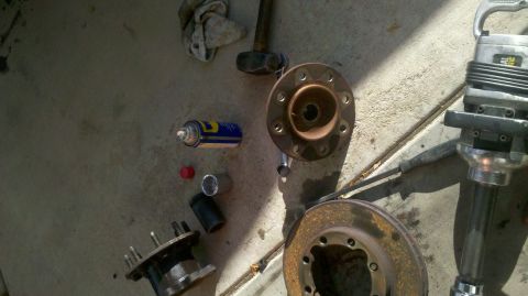 1997 Dodge 3500 - Tools and vehicle parts, including a wheel hub and brake rotor, are laid out on a concrete surface, suggesting front-end work.