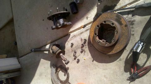 1997 Dodge 3500 - Disassembled vehicle brake components including a rotor, hub, and axle shaft are laid out on the ground.