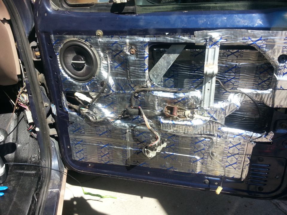 Car door panel removed showing sound deadening material, speaker, and internal door mechanisms