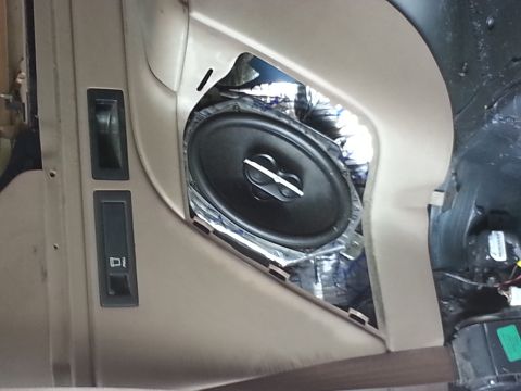 1994 Ford Bronco - Close-up of a car's interior door panel revealing a speaker installation with sound dampening material.