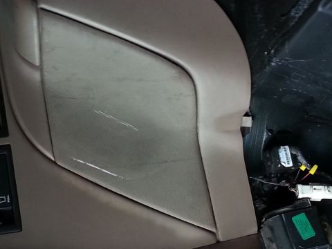 1994 Ford Bronco - The interior panel of a vehicle shows scuff marks and exposed wiring beneath.
