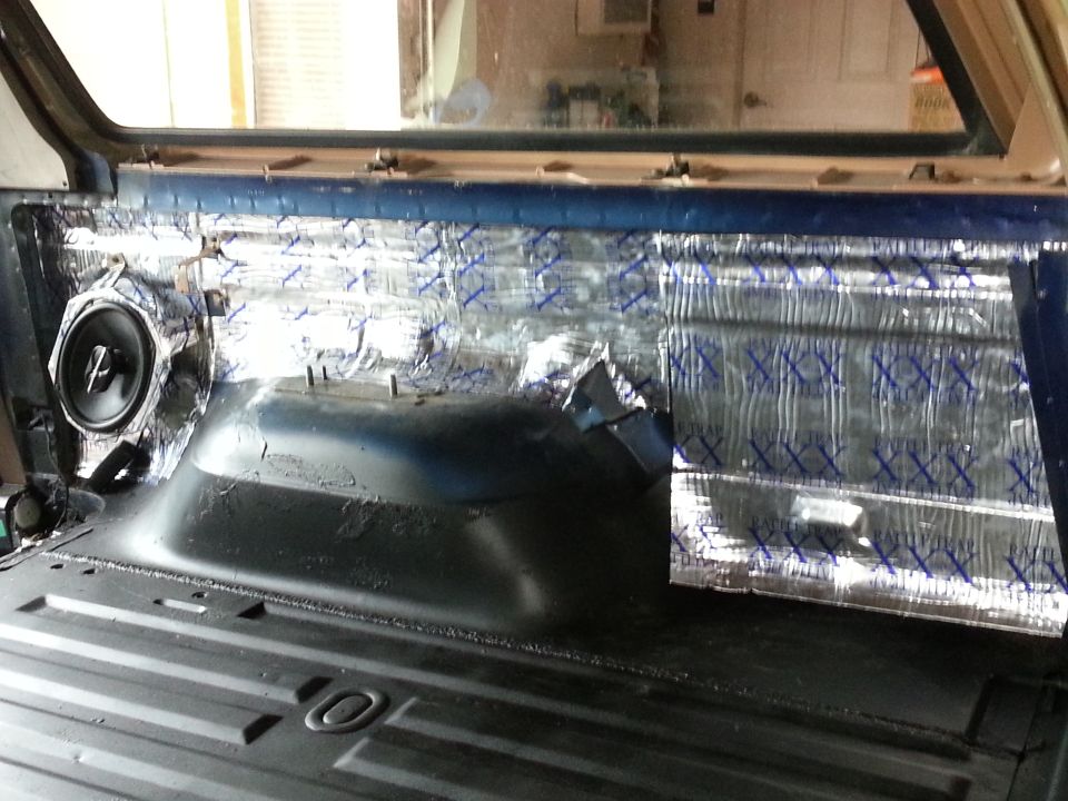Vehicle interior with sound dampening material on the rear panel and a speaker installed