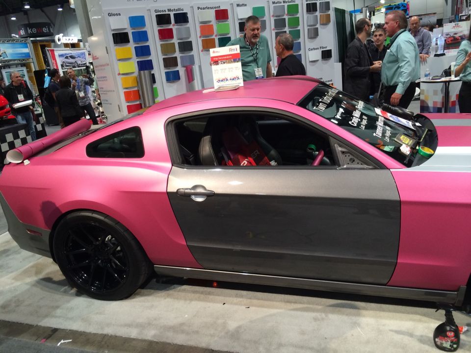 Pink and gray Ford Mustang with black wheels at an auto show