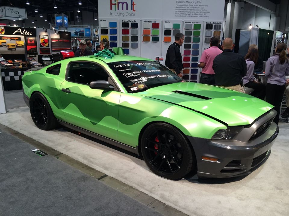 Green camouflage Ford Mustang at a trade show.