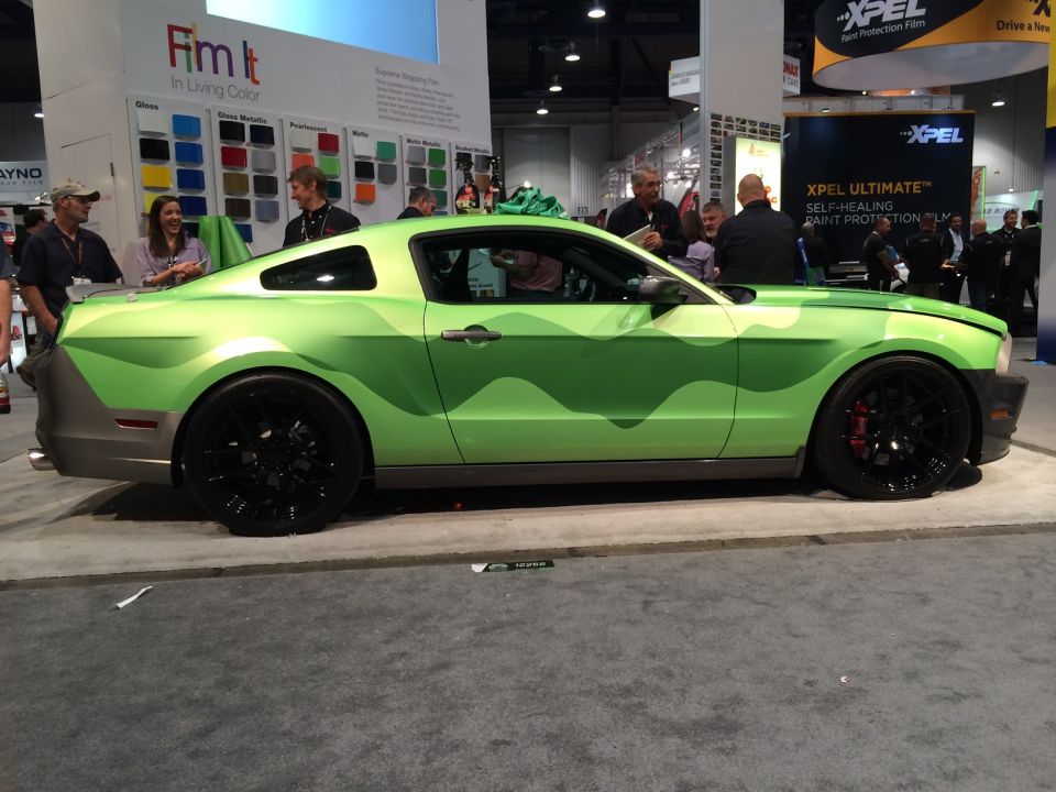 Lime green Ford Mustang with camouflage wrap and black wheels