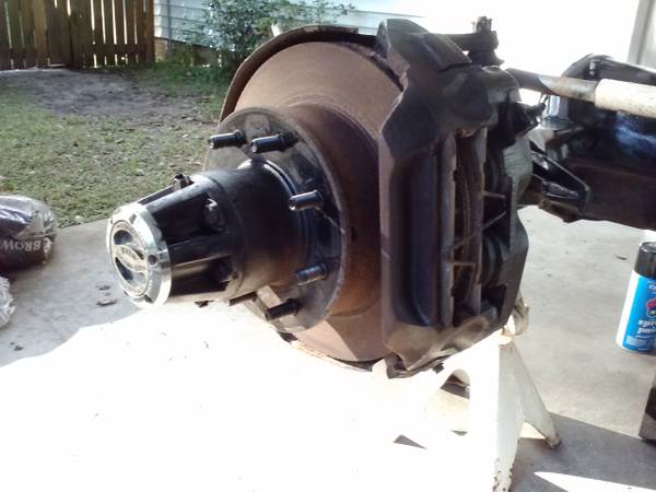 Vehicle hub assembly with brake rotor and caliper on a jack stand.