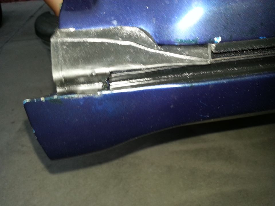 Blue body panel with bare-metal welded repair area