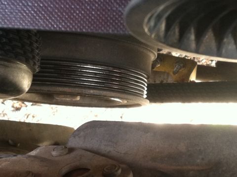 1992 Ford Bronco - A close-up view of a ribbed serpentine belt and pulley system, likely from a 1992 Ford Bronco, is shown. The metallic pulleys and the black…