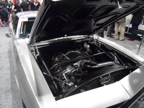 1971 Ford Ranchero - The engine bay of a classic silver car, likely a 1971 Ford Ranchero, is displayed with the hood open. The engine is a modern V8 with black…