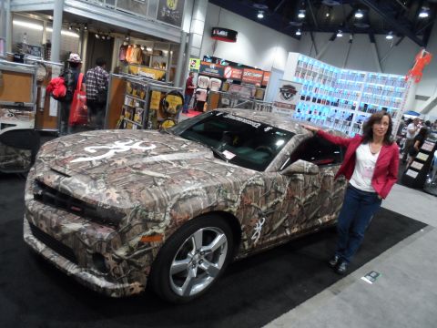 1971 Ford Ranchero - A woman poses next to a Chevrolet Camaro wrapped in a camouflage pattern with a large Browning logo on the hood. The car is on display at a…