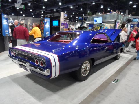 1971 Ford Ranchero - A vibrant blue 1968 Dodge Charger R/T with white and red racing stripes is displayed at an indoor event. The rear of the car is prominently…