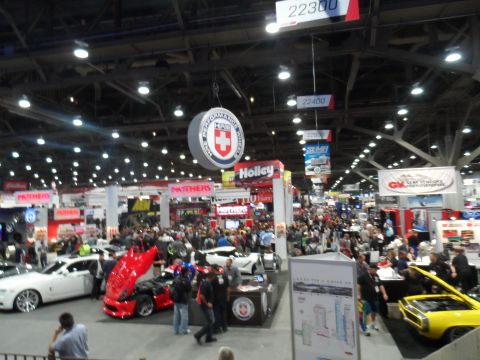 1971 Ford Ranchero - A red Ford Ranchero with its hood open is displayed at an indoor automotive show. The vehicle is surrounded by other cars and a large crowd…