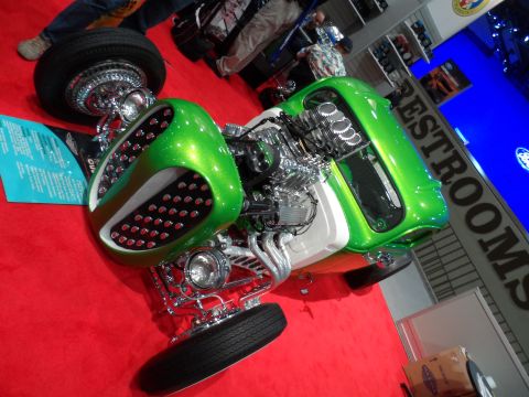 1971 Ford Ranchero - A custom-built hot rod with a bright green metallic body and a chrome engine is displayed on a red carpeted floor. The vehicle features a u…