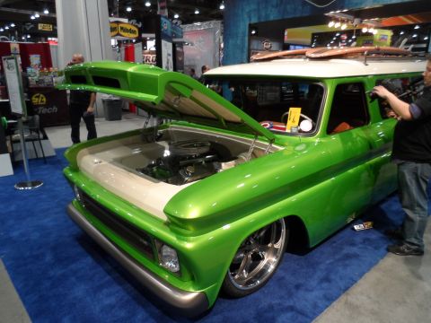 1971 Ford Ranchero - A highly customized, bright green vintage station wagon with its hood open, showcasing the engine bay. The vehicle is on display at an indo…