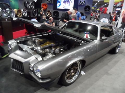 1971 Ford Ranchero - A highly modified, custom gray 1970s era coupe is displayed with its hood open, showcasing a complex engine with dual turbochargers. The ca…
