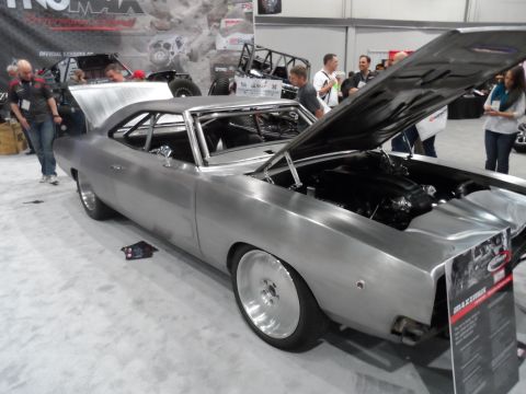1971 Ford Ranchero - A brushed metal 1971 Ford Ranchero with its hood open is displayed at an indoor event. The vehicle features a roll cage, custom wheels, and…