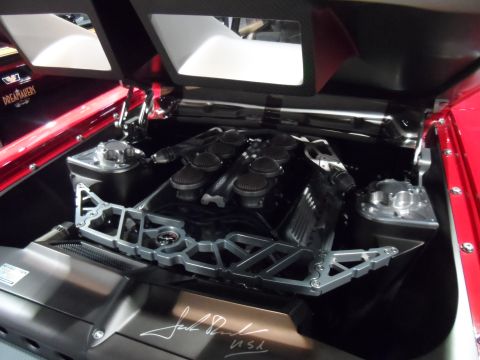 1971 Ford Ranchero - The engine bay of a red vehicle is shown, featuring a complex V8 engine with multiple air intakes and a custom silver structural brace. A s…